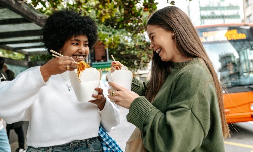two women outdoors eating