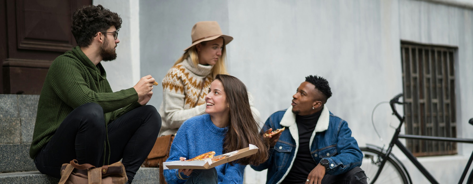 a group of people sharing pizza and drinks